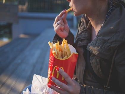 woman-in-brown-classic-trench-coat-eating-mcdo-fries