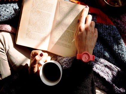 person-reading-book-and-holding-coffee